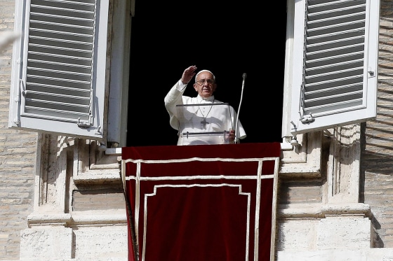 Pope Francis waves to the faithful from a window of the Apostolic Palace during the Angelus prayer in Saint Peter's Square.