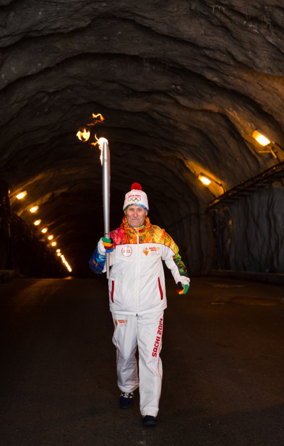 Nikolai Malykh carries the torch during the Olympic flame relay in a tunnel of a Siberian hydroelectric plant this week. Another torchbearer briefly caught fire.