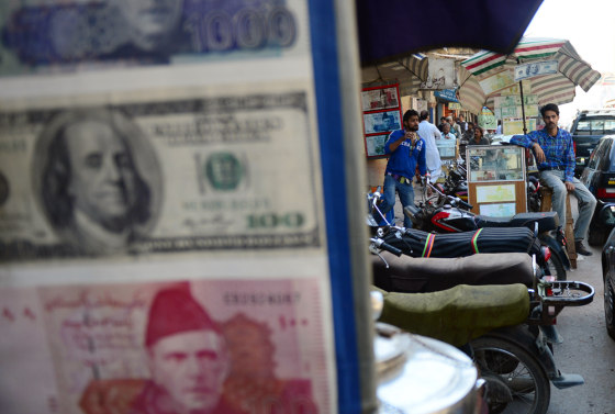 Currency dealers wait for customers at a roadside money exchange stall in Karachi, Pakistan.
