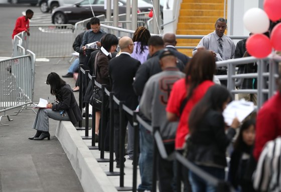 Job seekers fill out applications the old fashioned way as they wait in line to enter a job fair at a new Target retail store in August 2013 in San Francisco, Calif.