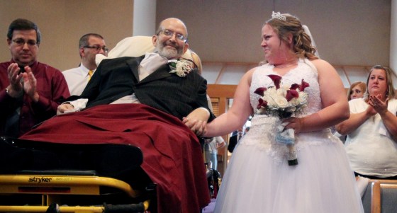 Family and friends begin to clap as Bride Sarah Nagy holds her father's hand as they wait for Reverend Charles Knerem to begin her wedding ceremony on Oct. 12, in Strongsville, Ohio.