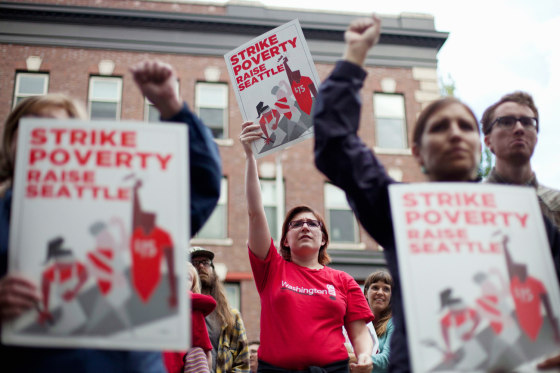 Joelle Craft, center, holds a sign during a rally and strike aimed at the fast-food industry and the minimum wage in Seattle.