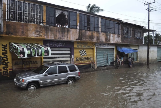 Residents look out from their homes as others stand on a street flooded by rain brought by Hurricane Raymond in Acapulco on Monday. Schools were closed and travel warnings were issued along Mexico's southern Pacific coast as a region still reeling from record flooding prepared for more precipitation from a major hurricane parked offshore.