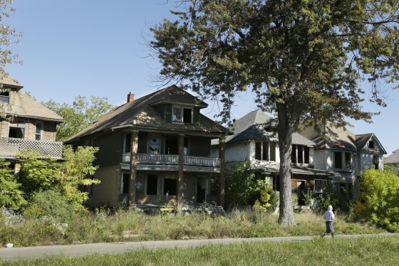 A young man walks in front of a row of abandoned houses in Detroit, Thursday, Sept. 26, 2013.