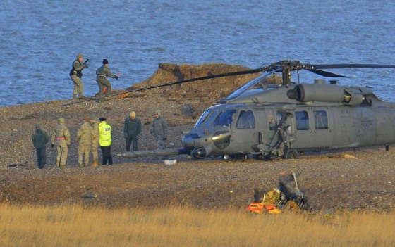 A Pave Hawk helicopter, military personnel and emergency services attend the scene where another helicopter crashed near the village of Cley in Norfolk, eastern England, on Wednesday.