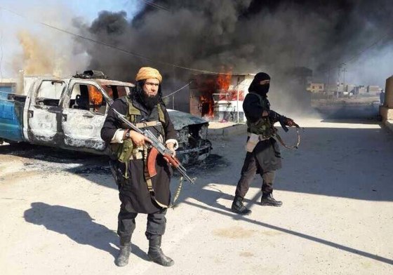 This undated image posted on a militant website on Jan. 4, 2014, shows Shakir Waheib, a senior member of the al Qaeda-linked Islamic State of Iraq and the Levant (ISIL), left, next to a burning police vehicle in Iraq's Anbar province.
