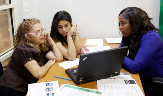 In this Friday, Dec 20, 2013 photo, certified enrollment specialist Richelle Baker, right, talks to Martha Medina, left, and her daughter Martha, both...