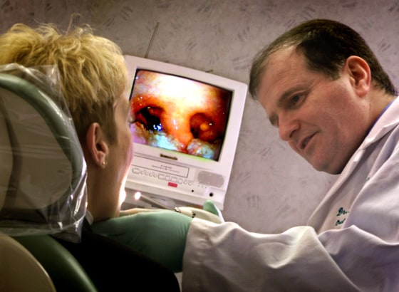 Dr. Mansoor Madani uses a miniature TV camera to get close look at an uvula, displayed on a monitor, during a tonsil procedure at his Philadelphia clinic.