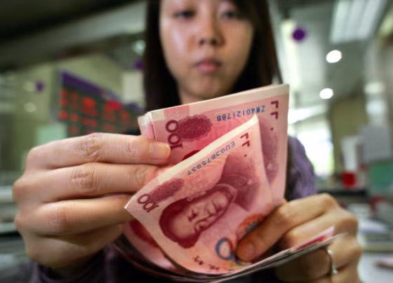 Image: bank teller counts Chinese currency.