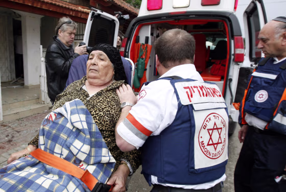 Image: Israeli paramedics evacuate an Israeli woman in shock following a rocket attack on the southern Israeli city of Sderot