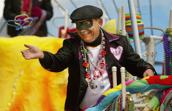 In this file photo,&nbsp;a masker tosses beads to the crowds as the Mobile Married Mystics take to the streets near Bienville Square in Mobile, Ala.