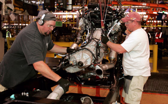 Image: Ford assemblymen mesh the engine to the drive shaft on the 2009 Ford F150 truck.