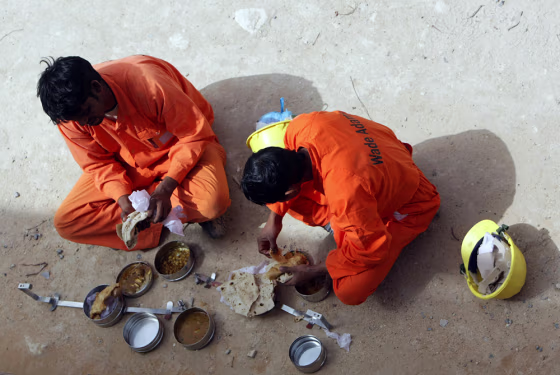 Image: Asian workers eat food during a break from their labours on a construction site