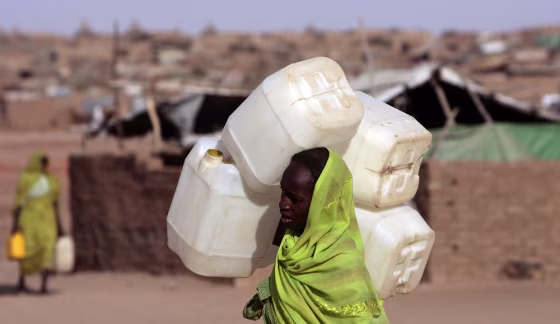 Image: A displaced Sudanese woman carries a jerrycan in search of water