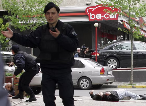 Image: A man takes cover, left, as a wounded man lies motionless