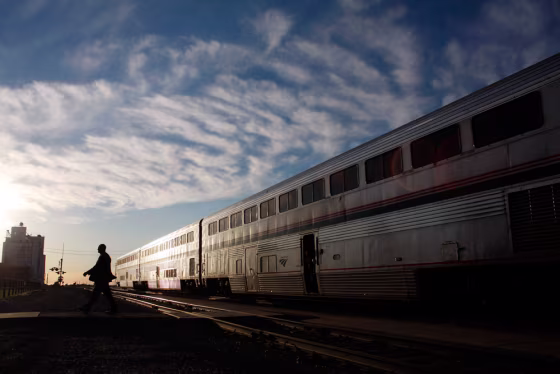 Image: An Amtrak train attendant walks across the tracks
