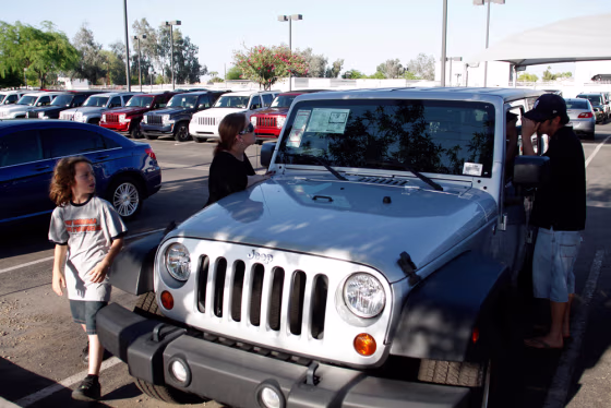 Image: David Quaranta III, Lisa Quaranta and David Quaranta II look at a Jeep vehicle at a Performance Chrysler Jeep Dodge dealership in Phoenix, Ariz.