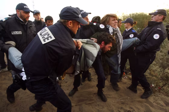 Image: French police officers remove migrants and protesters from the makeshift migrant camp known as 'The Jungle'