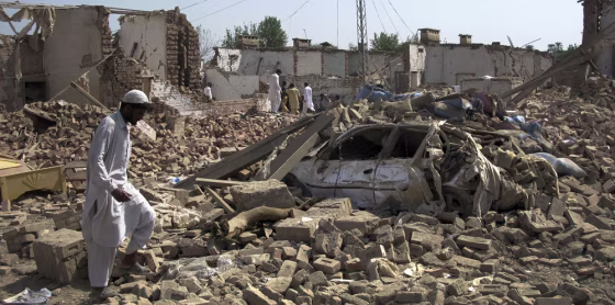 Image: A man walks on debris at the site of a suicide bomb attack in the town of Bannu