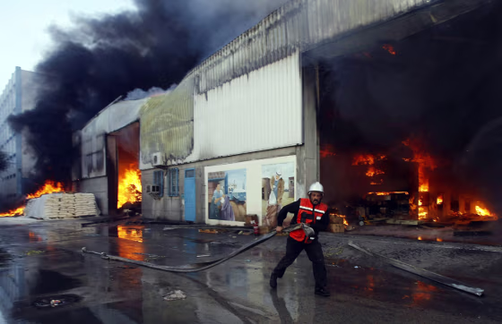 Image: Palestinian firemen extinguish fire at a U.N. warehouse in Gaza City