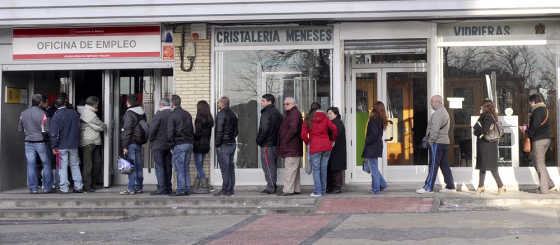 Image: People wait in line at a government employment office in Spain