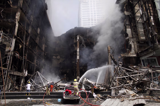 Image: Firemen try to extinguish fire at a shopping mall near anti-government \"red shirt\" protesters' abandoned stage in central Bangkok