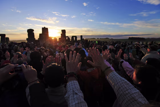 Image: People raise their hands while meditating during the summer solstice at Stonehenge