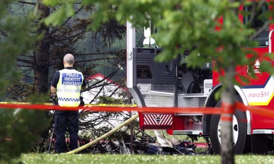 Image: A police officer looks at what is believed to be the remains of an airplane after a crash in Quebec City