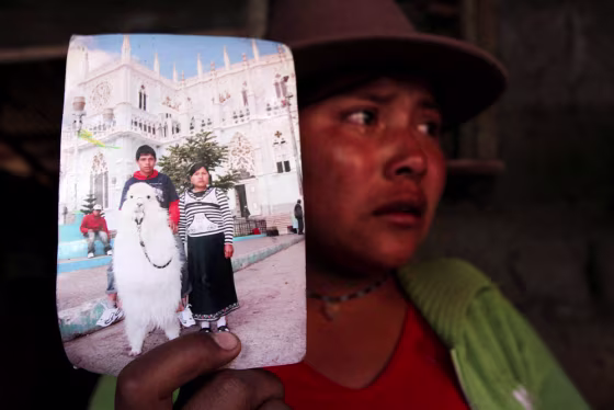 Image: Angelita Lala shows a photo of herself and her husband Luis Freddy Lala Pomavilla