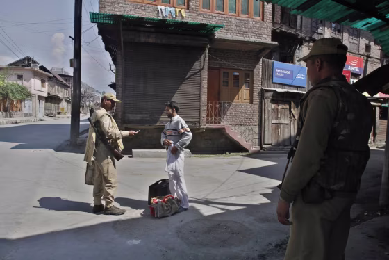 Image: An Indian paramilitary soldier checks the identity card of a civilian