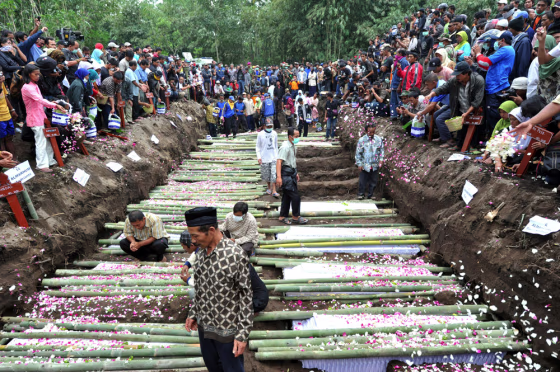 Image: Relatives sprinkle flower petals over the coffins of the victims of the Mount Merapi eruption during a mass funeral in Sidorejo