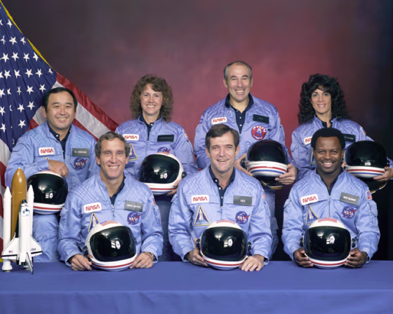 An official portrait shows the STS-51L crew members. Back row, left to right,&nbsp;are mission specialist Ellison S. Onizuka,&nbsp;teacher Christa McAuliffe, payload specialist Greg Jarvis and mission specialist Judy Resnik. In the front row are, left to right,&nbsp;pilot Mike Smith, commander Dick Scobee and mission specialist Ron McNair.