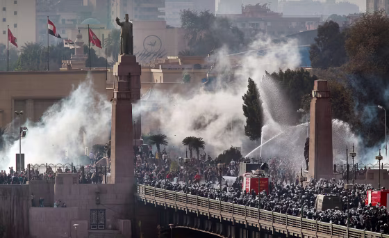 Image: Riot police force protestors back across the Kasr Al Nile Bridge