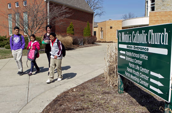 Image: Heather Coffy, right center, leaves the St. Monica School with her children in Indianapolis