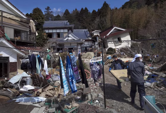 Image: The laundry of residents of Oshima island dry on a line as they carry Japanese tatami mats trying to clean their tsunami-damaged home in northeastern Japan