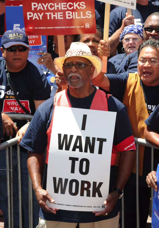 Image: A man holds a placard as he joins a protest of several thousand people and unionists demanding jobs outside City Hall in Los Angeles in this August 13, 2010 photo.