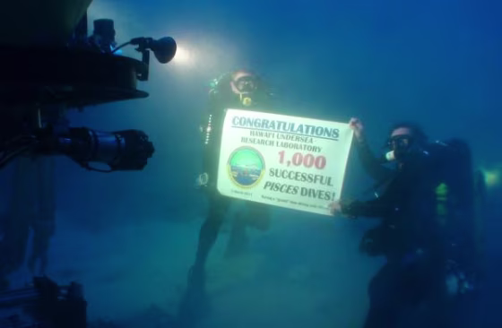 Divers Dave Pence, left, and Ken Longenecker&nbsp;hold up a banner commemorating the Hawaii Undersea Research Laboratory's 1,000th dive with the Pisces submersible.