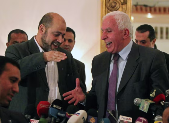 Image: Palestinian Fatah delegation chief Azzam al-Ahmed (R) shares a laugh with Hamas deputy leader Mussa Abu Marzuq (L) as they prepare to shake hands after a joint press conference in Cairo on April 27.