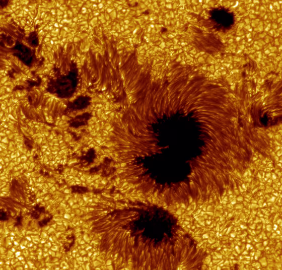 This large field-of-view image of sunspots in Active Region 10030 was observed on July 15, 2002. The relatively cool dark regions have temperatures of thousands of degrees Celsius, in contrast to the bright glowing gas flowing around the sunspots, which have a temperature of over 1 million degrees Celsius. (Researchers colored the image yellow for aesthetic reasons.)