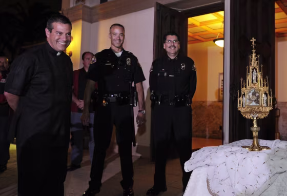 Image: Father Jose Magana, Long Beach police officer Jeff Liberman, and chief Robert Luna look at a 780-year-old religious relic after it was recovered