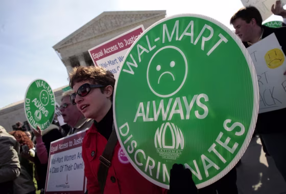 Image: File photo of protesters holding signs in front of the Supreme Court while class action lawsuit Dukes v. Wal-Mart is being argued inside the court in Washington