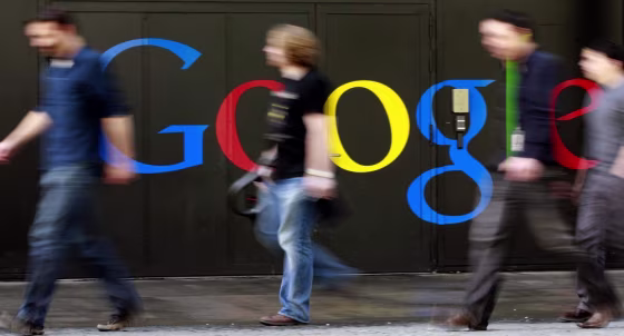Image: Photo of people walking past a logo next to the main entrance of the Google building in Zurich