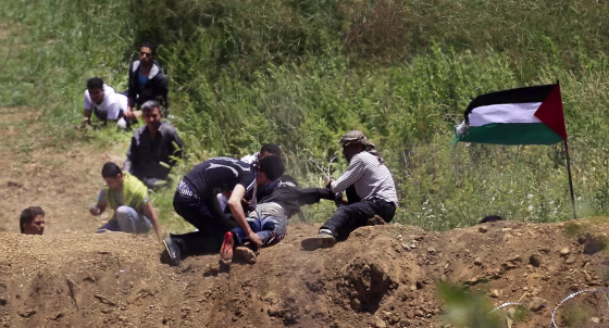 Image: A wounded protester is dragged away from the Syrian-Israeli border near Majdal Shams in the Golan Heights
