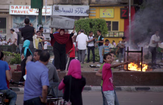 Image: An Egyptian vendor carries her chairs to escape fire following clashes at the center garden where protesters camp at Tahrir Square