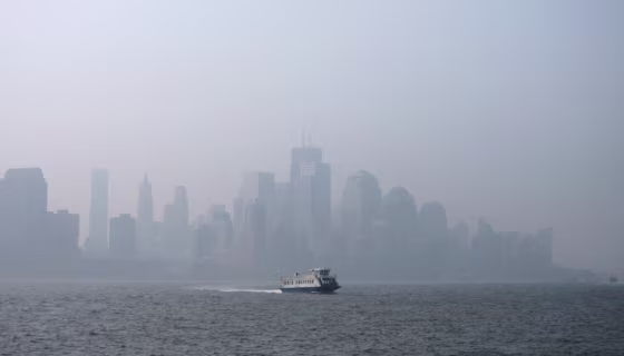 Image: A thick haze hangs over the skyline of Lower Manhattan as a ferry crosses the Hudson River in New York