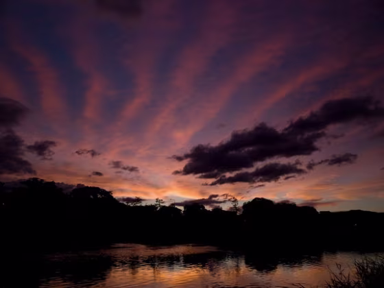Clouds create colorful stripes across the sky in this photograph taken at sunset.