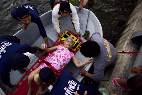 Image: Rescuers in Thailand help and elderlly woman
