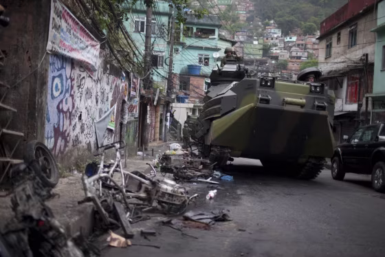 Image: A Brazilian navy armored vehicle runs over motorcycles as it moves into a Rio de Janeiro slum