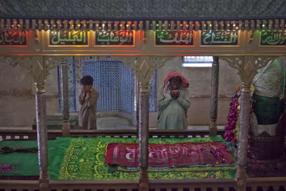 Image: Worshippers pray at the grave of Sufi Saint Abdullah Shah Ashabi in Thatta district, in Pakistan's Sindh province