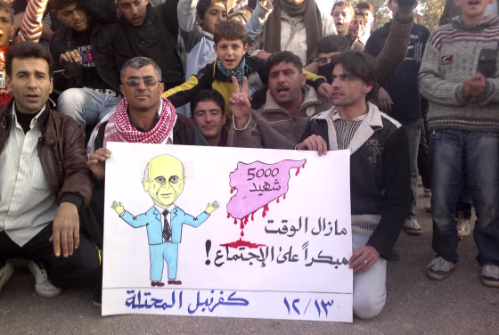 Image: Demonstrators against Syria's President al-Assad hold a poster with a picture representing Arab League Secretary General Elaraby in Kafranbel near Adlb